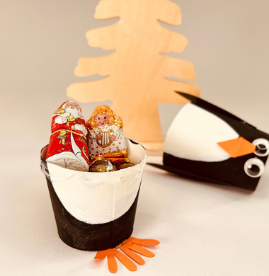 Ein Pinguin-Becher. Gebastelt aus einem Pappbecher, der mit Fotokarton, Farbe und Wackelaugen zu einem Pinguin wurde.