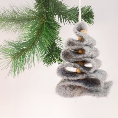 Ein Anhänger aus Filz, das in Form eines Weihnachtsbaumes zusammengefaltet wurde.