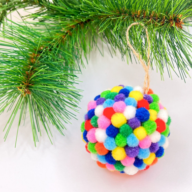 Ein Anhänger in Form einer Kugel, welche mit bunten Pompons überdeckt ist.