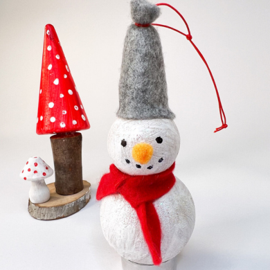 Ein Schneemann aus weißen Kugeln und einer Mütze sowie einem Schal aus Filz.