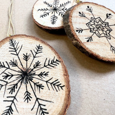 Bemalte Holzscheiben. Im Inneren wurde mit einem dünnen Fineliner eine Schneeflocke gemalt.