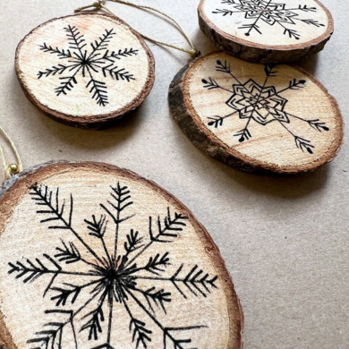Bemalte Holzscheiben. Im Inneren wurde mit einem dünnen Fineliner eine Schneeflocke gemalt.