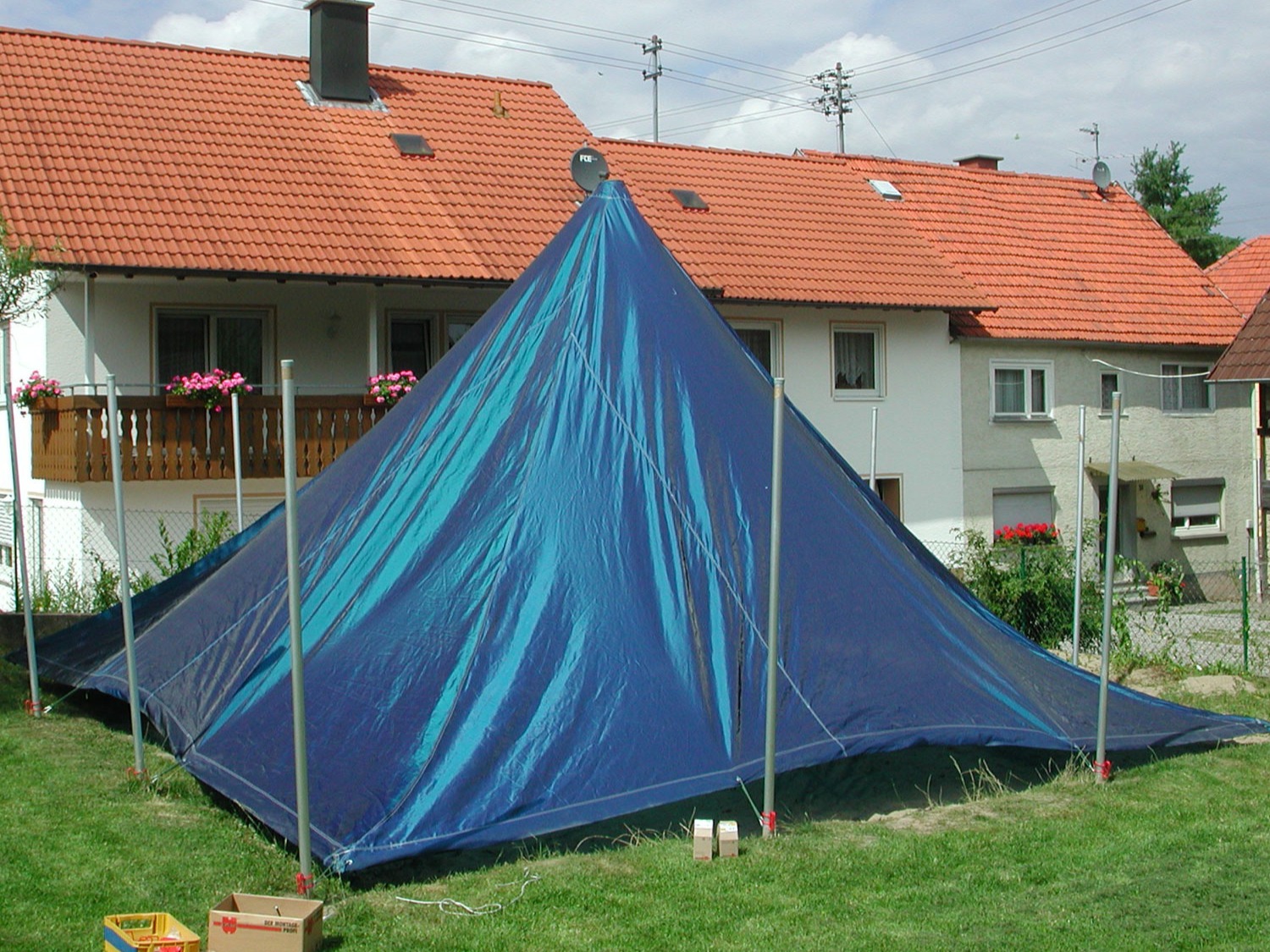 Maßgefertigte blaue Sandkastenabdeckung auf einem quadratischen Sandkasten im Garten.
