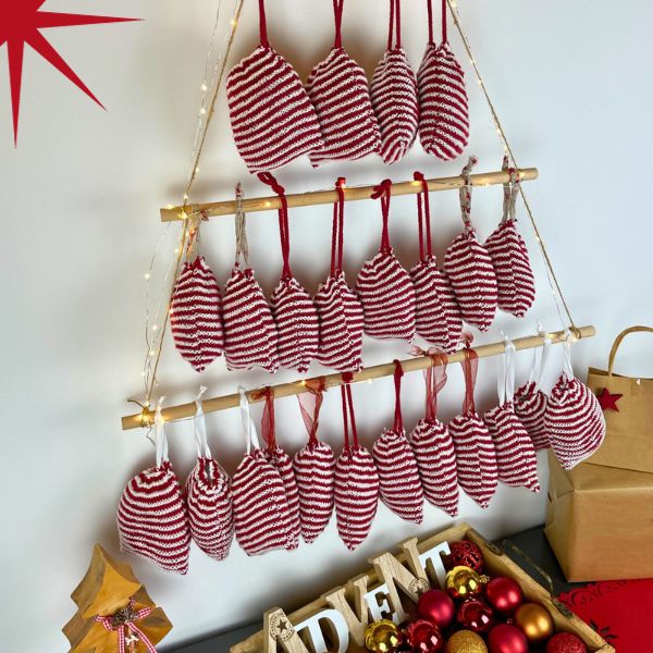 Adventskalender Säckchen als Tannenbaum aufgehangen im Illusionsstricken in rot und weiß.
