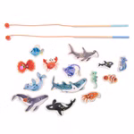 Das Angelspiel Paulie von Moulin Roty zeigt zwei hölzerne Angelruten mit roten Schnüren die über farbenfrohen hölzernen Meeresbewohnern wie Fischen Walen Haien Orcas Krabben und Tintenfischen auf einem weißen Hintergrund platziert sind.