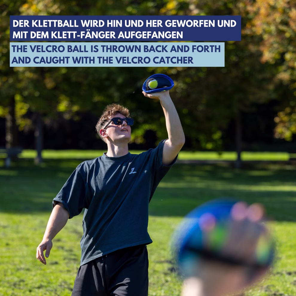 Schildkröt Neopren Klettball Set mit einem Ball _32563 Ein junger Mann mit Sonnenbrille spielt mit dem Schildkröt Neopren Klettball Set mit einem Ball in einem sonnigen Park Fangen während ein anderer einen Klettverschluss-Fänger hält; deutscher und englischer Text überlagert das Bild.