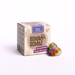 Eine Schachtel SchokoSchatz für Lieblingsmenschen - Ein Herz für Dich steht neben einer runden Schokoladenkugel und einer kleinen herzförmig verpackten Speckstein von SchokoSchatz auf weißem Hintergrund.