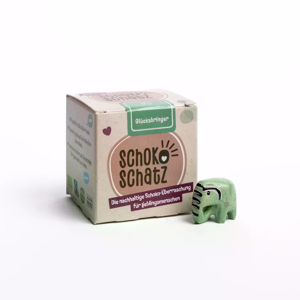 SchokoSchatz SchokoSchatz für Lieblingsmenschen Glücksbringer_30411 Eine SchokoSchatz für Lieblingsmenschen Glücksbringer-Box eine dunkle Schokoladenkugel und eine grüne Elefantenfigur von SchokoSchatz stehen nebeneinander auf weißem Hintergrund.