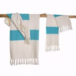 HängemattenGlück Strandtuch aus Bio-Baumwolle zweifarbig in 7 Farbkombinationen _31623 weiß-blau Zwei Strandtücher aus Bio-Baumwolle von HängemattenGlück in Weiß mit breiten türkisfarbenen Streifen und Fransen hängen dekorativ an einer rustikalen Holzstange vor weißem Hintergrund. weiß-blau