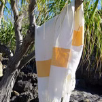 HängemattenGlück Strandtuch aus Bio-Baumwolle zweifarbig in 7 Farbkombinationen _31625 weiß-orange Das Strandtuch aus Bio-Baumwolle von HängemattenGlück hier in einer gelb-weißen Farbkombination hängt über einem Ast mit grünem Laub und steinigem Boden im Sonnenlicht. weiß-orange