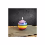 Die brennende Kerze Kerze Ball von Himalaya Salt Dreams mehrfarbig und mit einem Durchmesser von ca. 10 cm steht auf einer grauen Fläche mit einer dunkel strukturierten Wand im Hintergrund und einem Holztisch darunter.