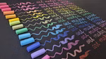 Mercurius Art Makes Sense Tafelpastellkreide sortiert 16 Farben wird zum Zeichnen von Wellenlinien und zum wiederholten Schreiben von "art makes sense" auf schwarzes Papier verwendet wobei jeder Satz der Kreidefarbe in einem gelb-rosa Spektrum entspricht.