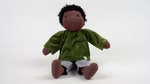 Puppe Leon nach Waldorfart Dunkelhäutige Stoffpuppe mit kurzen schwarzen Locken, grünem Oberteil und heller Hose, sitzend vor weißem Hintergrund.
