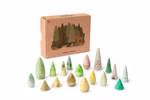 Achtzehn handbemalte Holzfiguren in verschiedenen Grün- und Brauntönen, die unterschiedliche abstrakte Baumformen und Zapfen für eine kleine Waldlandschaft darstellen, vor der Verpackung. 