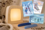 Toverlux Lampe aus hellem Holz mit drei winterlichen Waldorfkind Postkarten und 2 Kartenständern in Blautönen vor weißem Hintergrund.