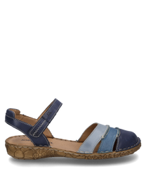 Die Sandale hat einen Klettverschluss und besteht aus glattem blauem Leder in verschiedenen Blautönen. Die Sohle ist hellbraun mit einem floralen Muster geprägt und bietet einen komfortablen Halt.