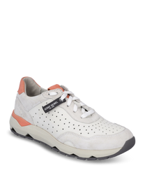 La zapatilla está hecha de cuero liso color crema con un diseño perforado y acentos naranjas. Cuenta con un sistema de cordones y una suela robusta de color beige para un soporte y comodidad óptimos.