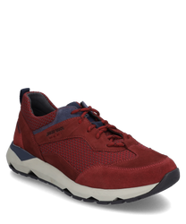 Zapatilla roja con cordoneshecha de gamuza y textil. El zapato tiene una suela blanca en contraste y acentos azuleslo que le da un aspecto deportivo.