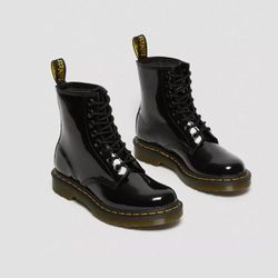 Schwarze Lackleder-Boots mit Schnürung und gelber Naht auf dicker Sohle. Die glänzende Oberfläche und die robuste Konstruktion verleihen den Stiefeletten einen klassischen und zugleich modernen Look.