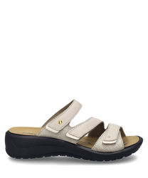 La sandalia color crema tiene un cierre de velcro y un material superior texturizado. Cuenta con una suela cómoda y discretas aplicaciones doradas.