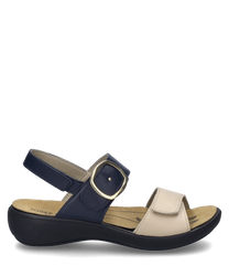 Die creme-dunkelblaue Sandale verfügt über einen Klettverschluss und eine breite hellcremefarbene Riemenstruktur aus Leder. Der Schuh hat eine abgerundete Sohle und eine große goldene Schnalle als besonderes Merkmal.