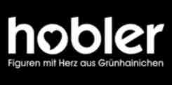 Schriftzug hobler in weiß auf schwarzem Hintergrund darunter Text Figuren mit Herz aus Grünhainichen Herzsymbol im Buchstaben o integriert