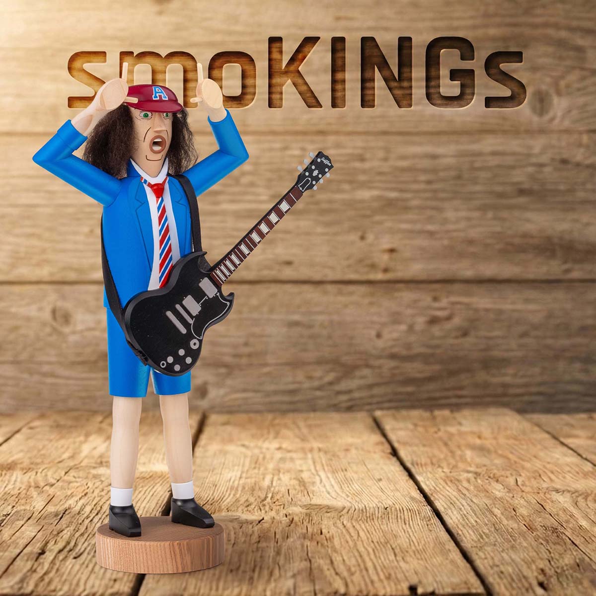 Räuchermännchen Angus auf Holzsockel mit knallblauer Schuluniform mit kurzen Hosen Sakko gestreifter Krawatte schwarzer E-Gitarre wilde Mähne unter der roten Kappe (mit dem markanten 