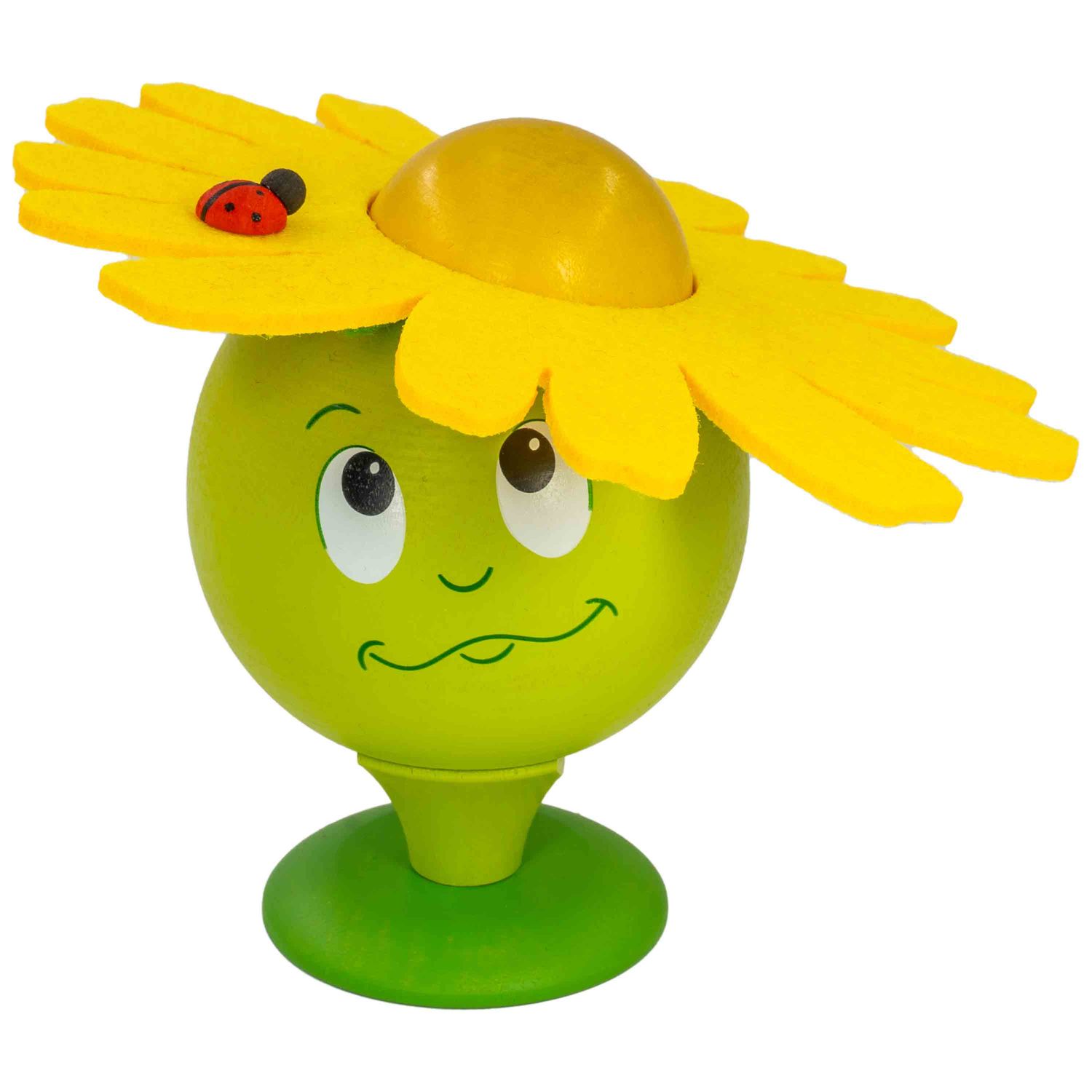Eine grüne Räucherblume mit gelbem Blumenhut und Gesicht steht auf grünem Sockel Eine Marienkäferfigur sitzt auf dem Hut