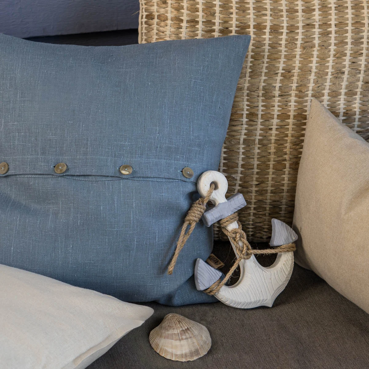 blaues Jeans Kissen,  Kissen mit Bast natur und cremefarbenes Baumwoll Kissen und  eine Muschel  und Anker als Deko