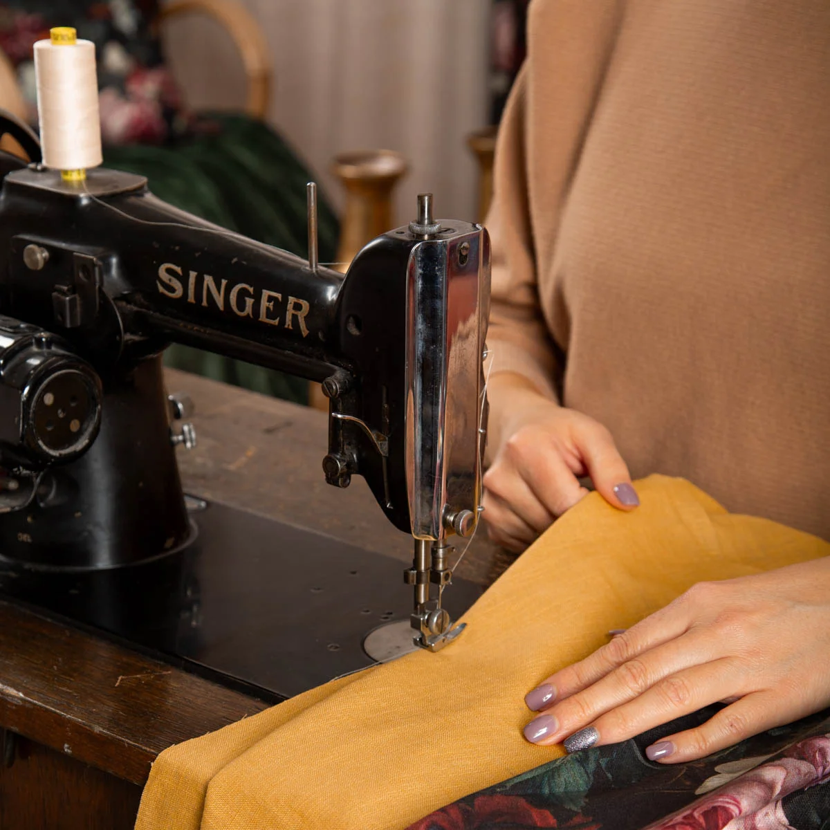Nahaufnahme einer Vintage-Nähmaschine, an der eine Person einen gelben Dekostoff bearbeitet. Hände führen den Stoff durch die Maschine für ein DIY-Nähprojekt wie z.B. Vorhänge