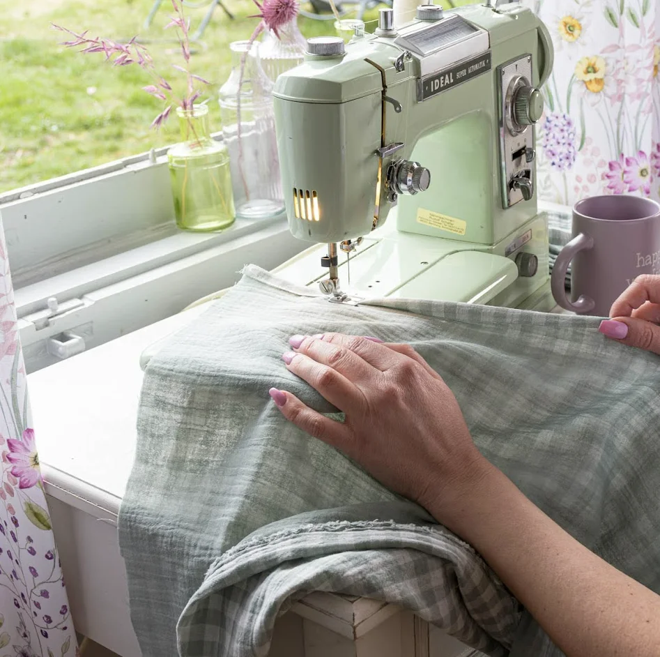 Nähmaschine auf einem hellen Nähtisch mit Stoffe Meterware, die für Gardinen verarbeitet wird