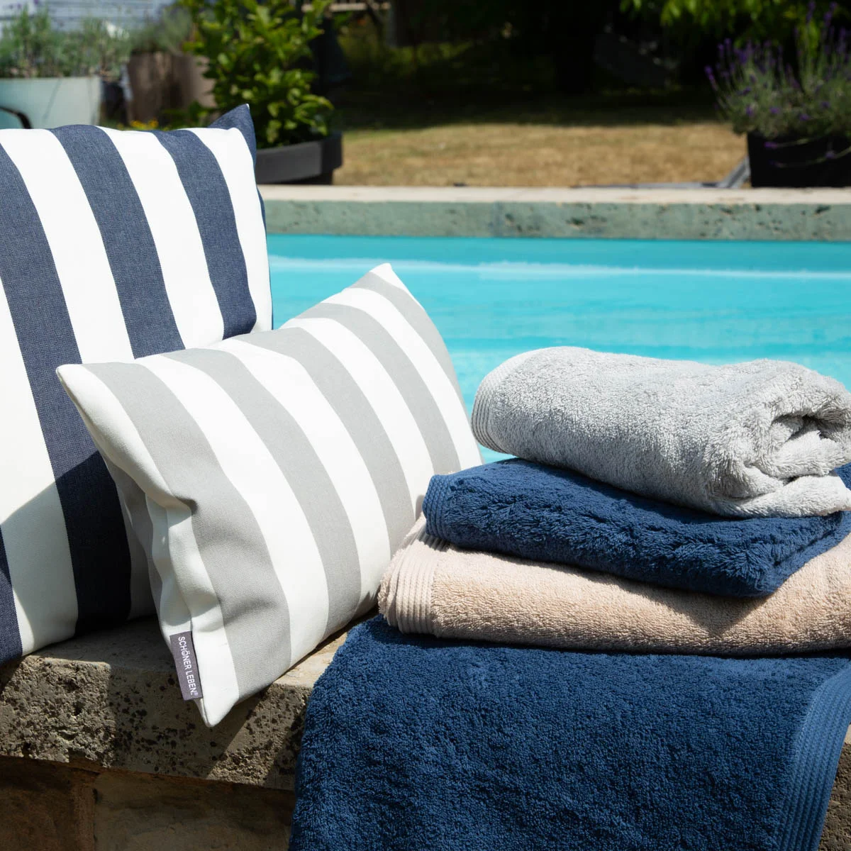 Gestreifte Outdoorstoffe in Blau, Weiß und Grau, dekorativ arrangiert am Pool
