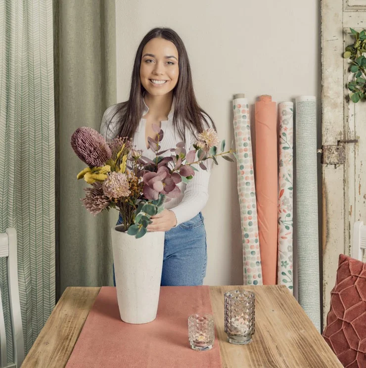 Stoffe meterware dekoriert für Frühling und genäht als Vorhang mit Frau und Blumenstrauß auf einem Esstisch