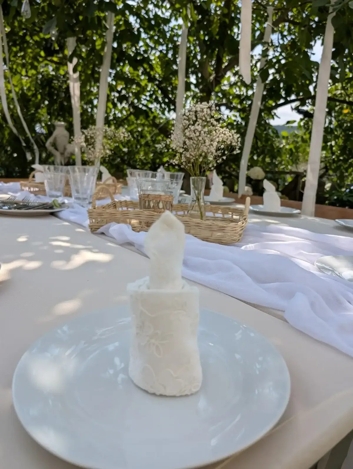 Festlich gedeckter Tisch in Weiß – Stoffservietten, Glasvasen mit Schleierkraut und Stoffläufer.