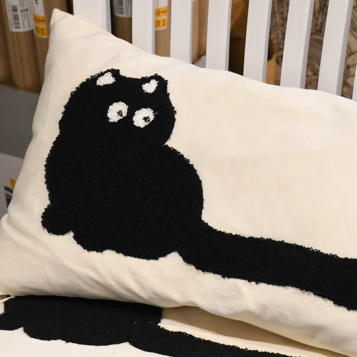 Ein cremefarbenes Kissen mit einer schwarzen Katze als Applikation von SCHÖNER LEBEN