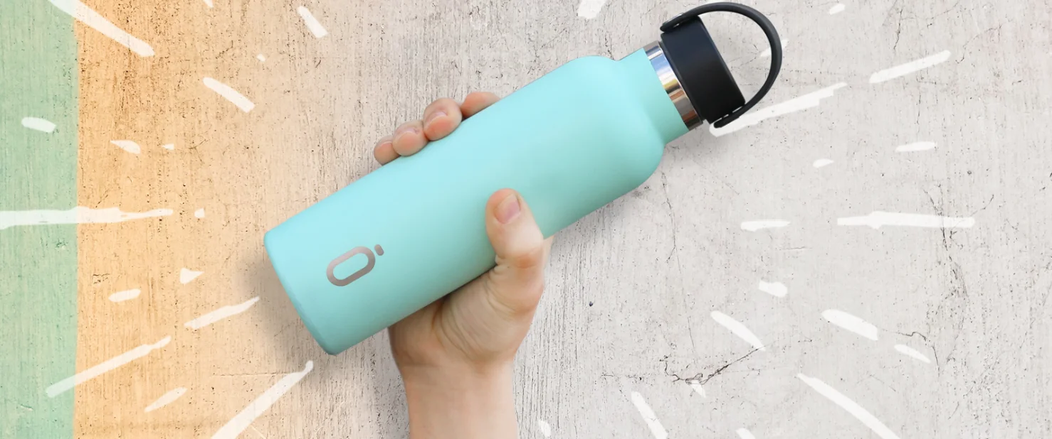 Hand hält mintfarbene Runbott Trinkflasche vor kreativ gestaltetem Hintergrund – nachhaltige Geschenkidee für jeden Tag