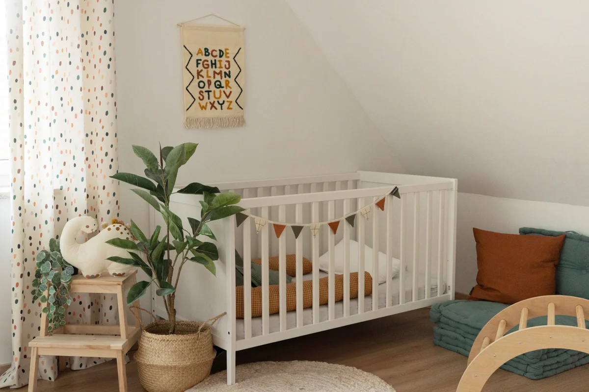 Kinderzimmer mit Gitterbett mit Heimtextilien in Orange und Petrol