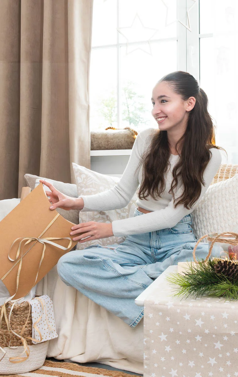 Frau sitzt auf dem Sofa und packt Geschenke ein