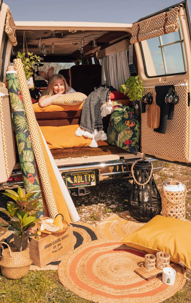 Frau liegt auf gelben Kissen in einem Campervan Frau liegt auf gelben Kissen in einem Campervan