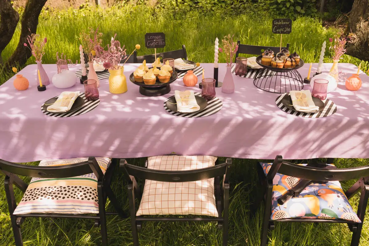 Gedeckter Tisch im Garten mit violetter Tischdecke