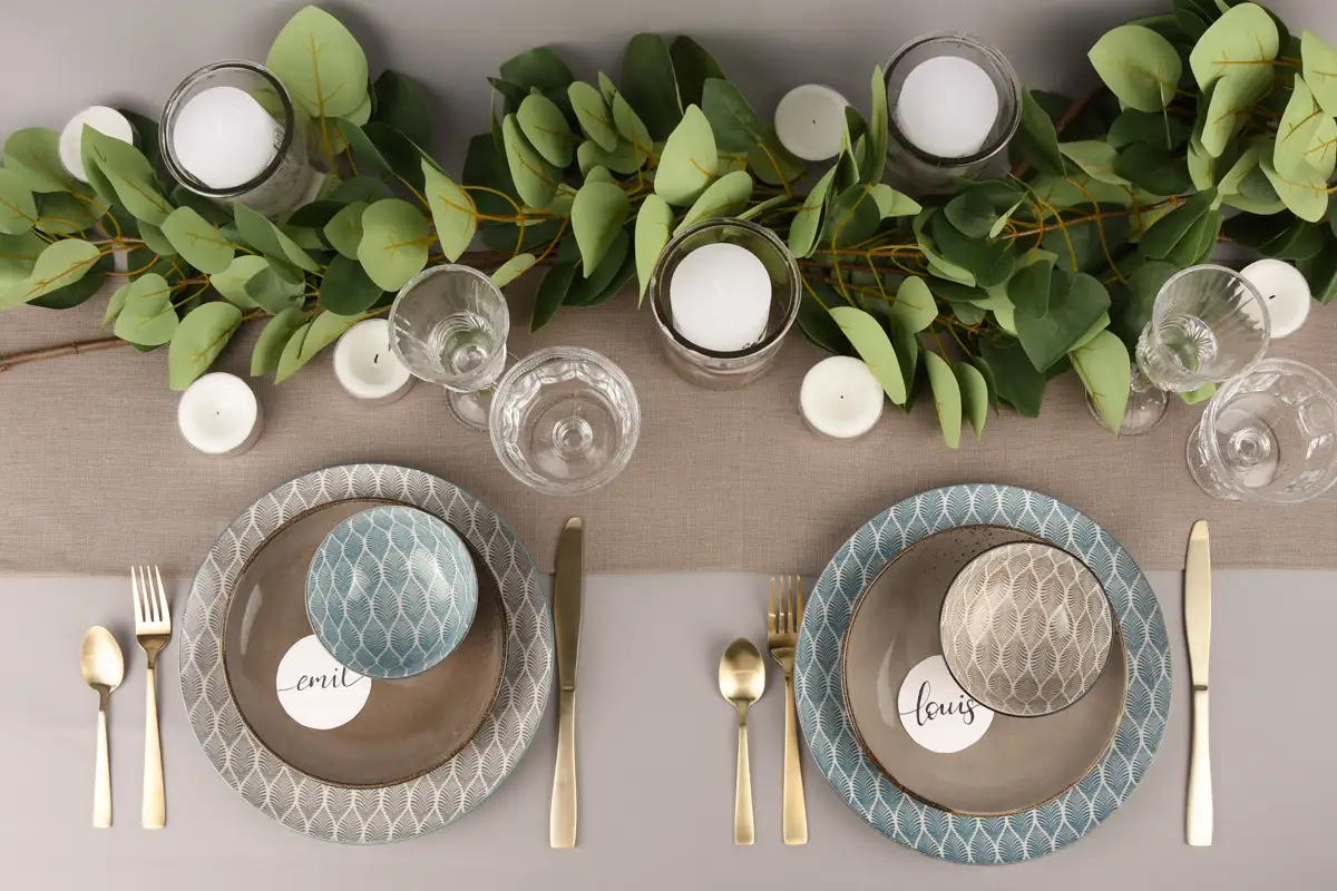 Gedeckter Tisch mit gemustertem Geschirr auf grauer Tischdecke