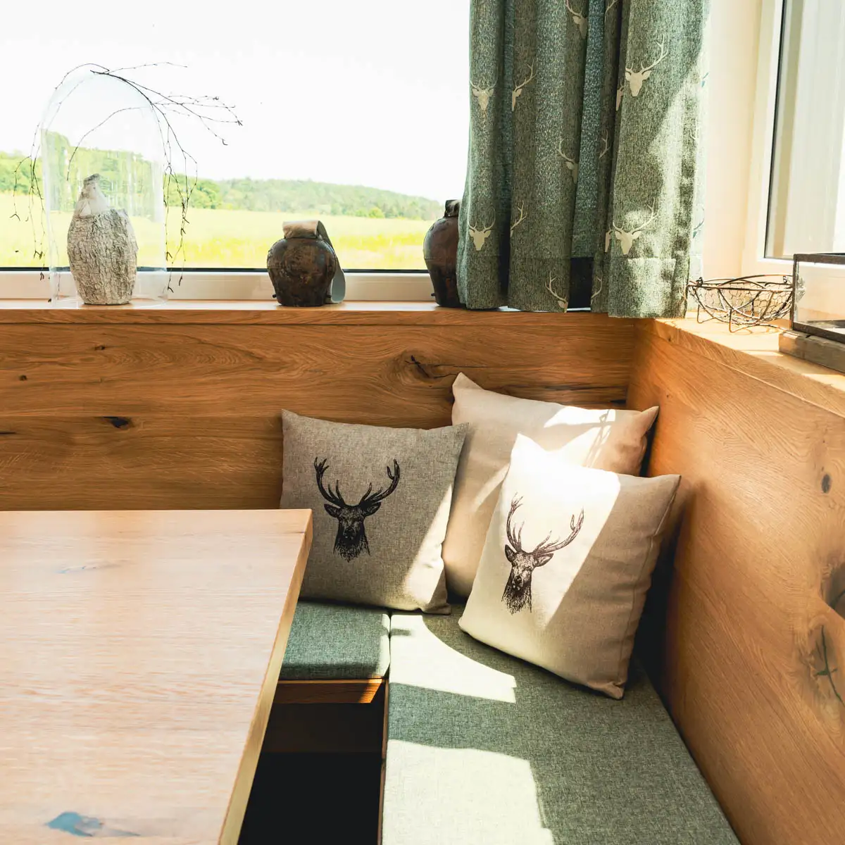 Landhauskissen mit Hirschmotiv auf einer Eckbank in einem Landhaussesszimmer