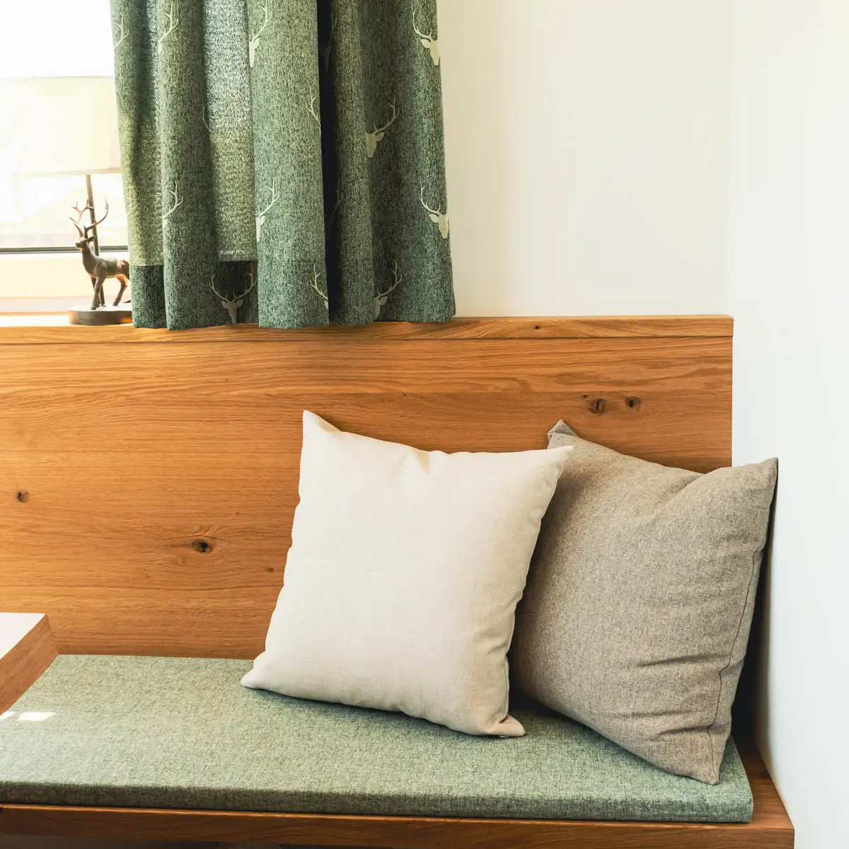 Eckbank in einem Landhausesszimmer mit Landhauskissen, Landhausdeko und Landhausgardinen mit Hirschmotiv