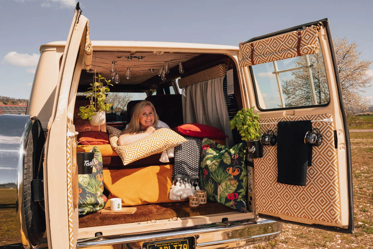 Frau liegt in einem Campervan auf Outdoorkissen in gelb