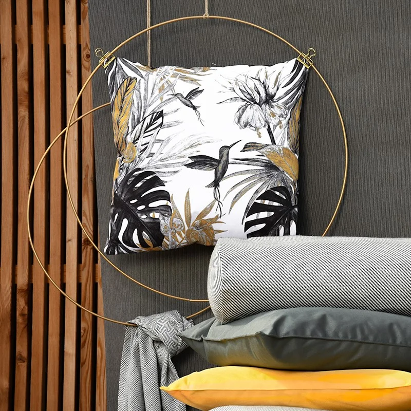 Outdoorkissen in weiß mit Palmenblättern und Kolibri hängt in einem Metallring
