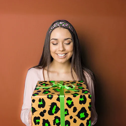 Frau hält ein in Leopardenmuster verpacktes Geschenk in der  Hand
