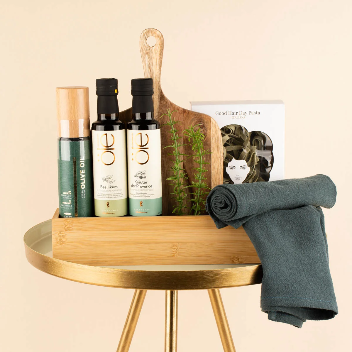 kulinarische Geschenke wie verschiedene Olivenöle und Nudeln, angerichtet auf einem goldenen Beistelltisch