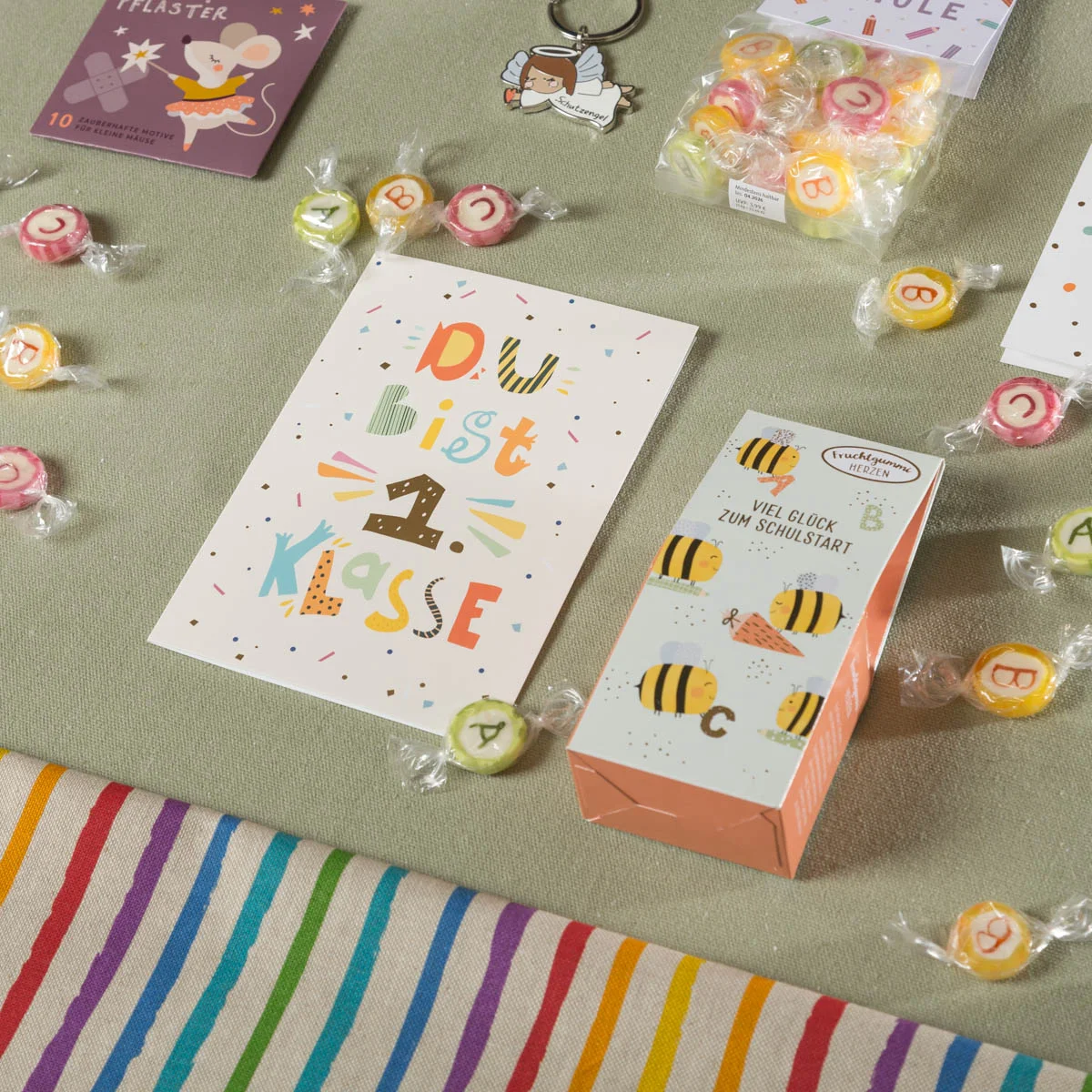 Fröhliches Einschulungsset mit bunter Postkarte „Du bist 1. Klasse!“, Glücksbox mit Bienenmotiv, ABC-Bonbons, Trostpflaster, Schlüsselanhänger und Miniheft – perfekte Inhalte für die Schultüte