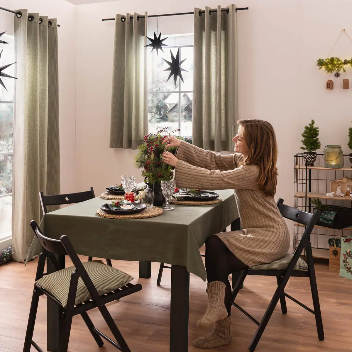 Frau sitzt an einem weihnachtlich gedeckten Tisch