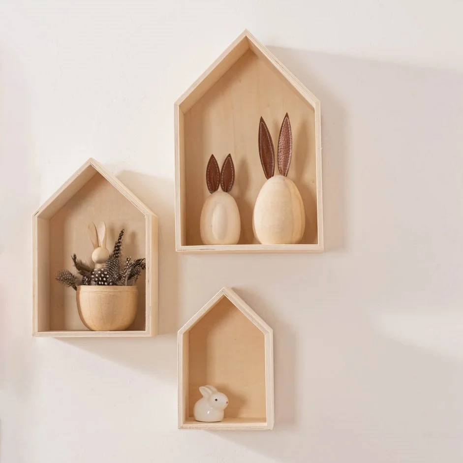 3 Kleine Regale in Häuserform hängen an der Wand und sind mit Osterfiguren dekoriert